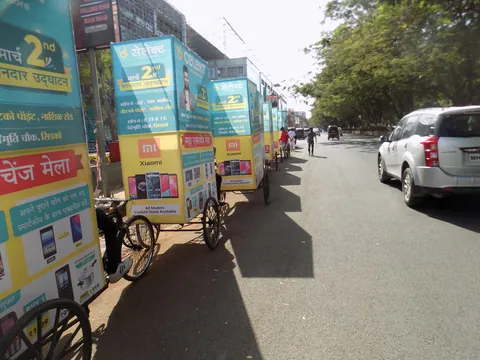 Branded advertising tricycles lined up along a city road